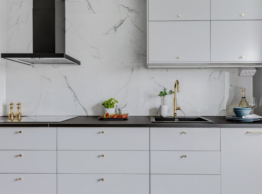 Nyspacklade och målade väggar i kök med marmoryta och gyllene detaljer – Kulladal, Malmö.